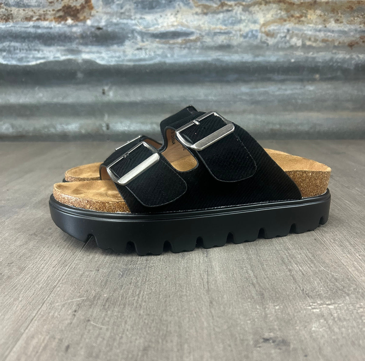 Black sandal with cork sole on a textured surface
